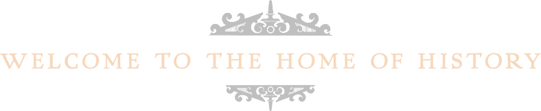 A decorative sign with ornate black detailing reads "Welcome to the Home of History" in bold, light-colored letters.